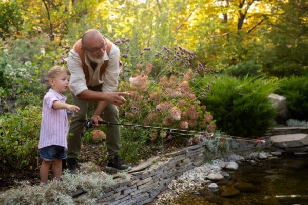 Grandfather and grandson fishing together in a pond.