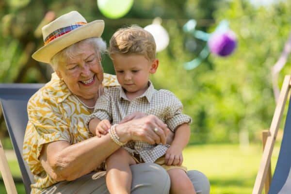 Grandson sitting on his grandmother's lap in the garden.