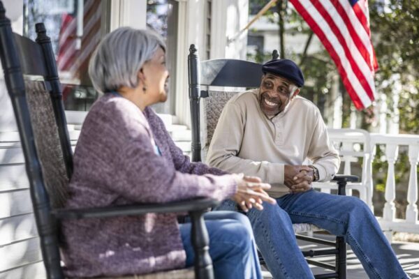 Senior couple talking in rocking chairs on front porch