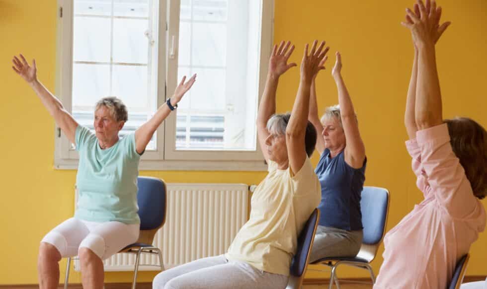 active senior women in yoga class exercisig on chairs